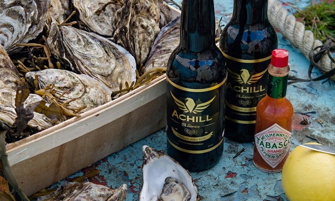 Gift box with Achill brewery beer, shucked oyster, lemon and tobasco sauce on the sole of the boat